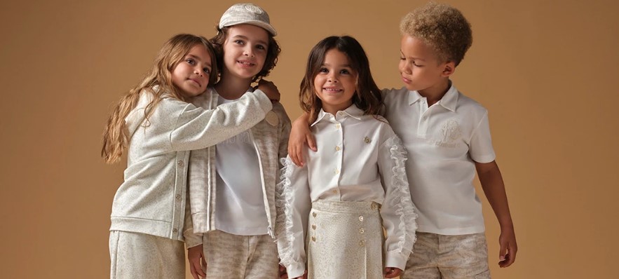 Četvero djece u elegantnoj bež odjeći stoji zagrljena