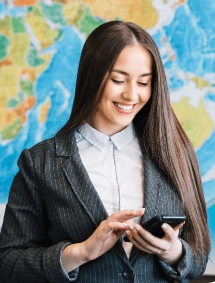 Nasmejana žena u odelu koristi mobitel ispred karte