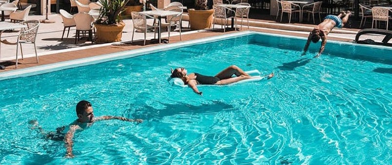 Troje ljudi plivaju u hotelskom bazenu