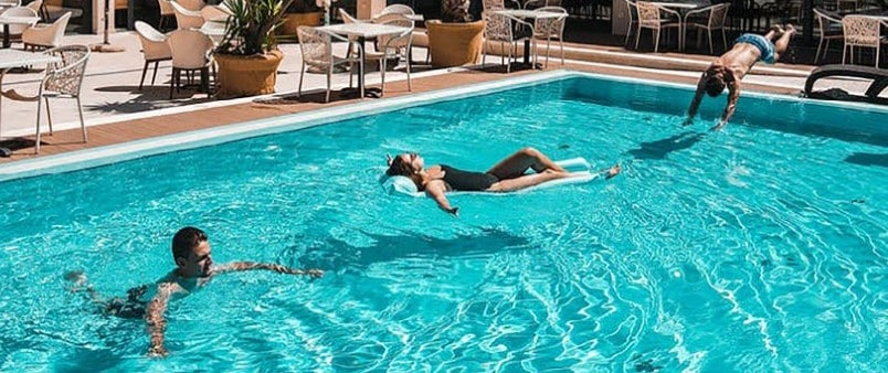 Troje ljudi plivaju u hotelskom bazenu