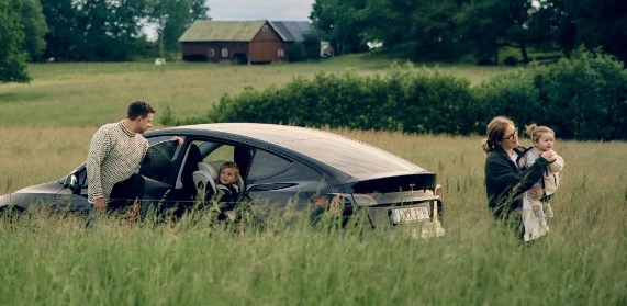 Obitelj s djecom kraj automobila na livadi