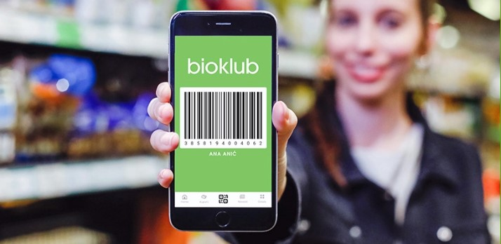 Djevojka u trgovini drži mobitel s prikazanim barkodom