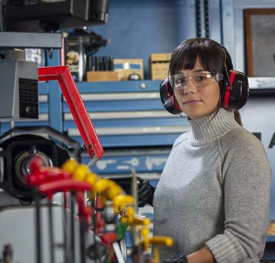 Žena u radionici s naočalama i zaštitnim slušalicama