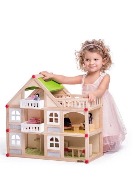 Djevojčica kleči pored drvene kućice za lutke