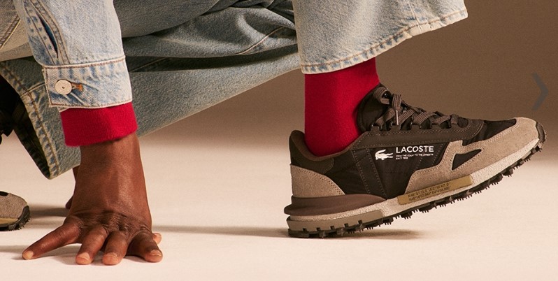 Muška ruka na podu i noga u Lacoste braon patikama